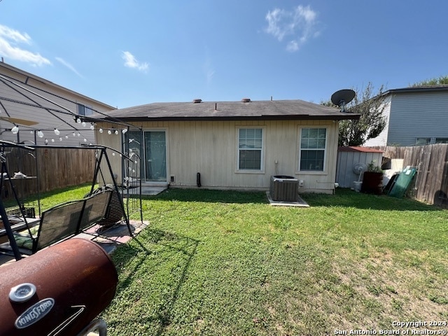 back of house featuring central AC unit and a yard