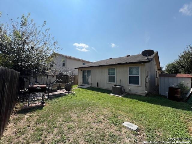 10131 Southern Sun, San Antonio, TX 78245 - rear view of house with central AC unit, a fenced backyard, a yard, and an outbuilding
