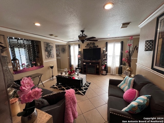 living room with ceiling fan, light tile patterned floors, ornamental molding, and a textured ceiling