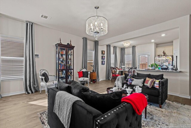 living room with light hardwood / wood-style floors and a notable chandelier