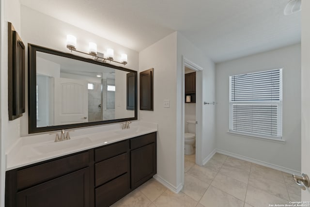 bathroom with vanity, toilet, plenty of natural light, and tiled shower