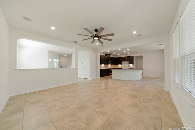 unfurnished living room with ceiling fan, light tile patterned flooring, and sink