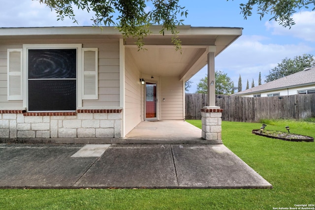 entrance to property featuring a yard and a patio