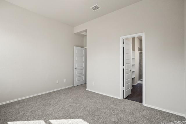 unfurnished bedroom featuring dark colored carpet and a walk in closet