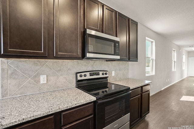 kitchen featuring light stone countertops, stainless steel appliances, backsplash, and dark brown cabinetry