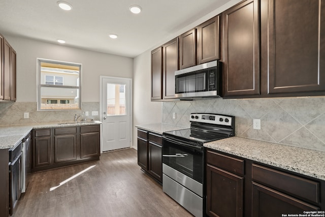 kitchen featuring sink, tasteful backsplash, dark brown cabinets, appliances with stainless steel finishes, and dark hardwood / wood-style flooring