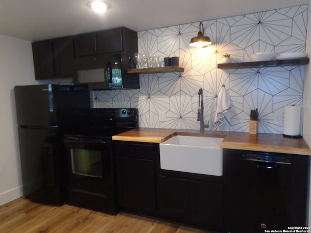 kitchen with light wood-type flooring, black appliances, decorative backsplash, and sink