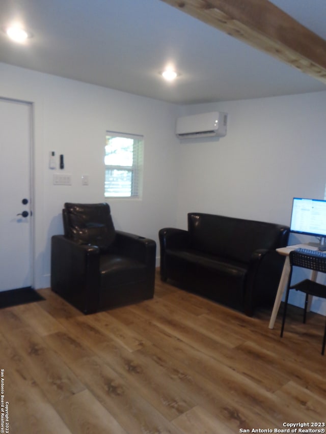 living room featuring beamed ceiling, hardwood / wood-style flooring, and a wall mounted AC