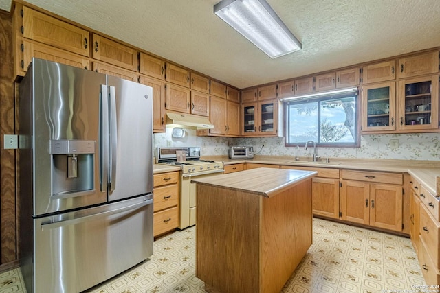 kitchen with stainless steel fridge, sink, a kitchen island, a textured ceiling, and white stove