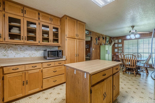 kitchen with ceiling fan, a textured ceiling, and a kitchen island