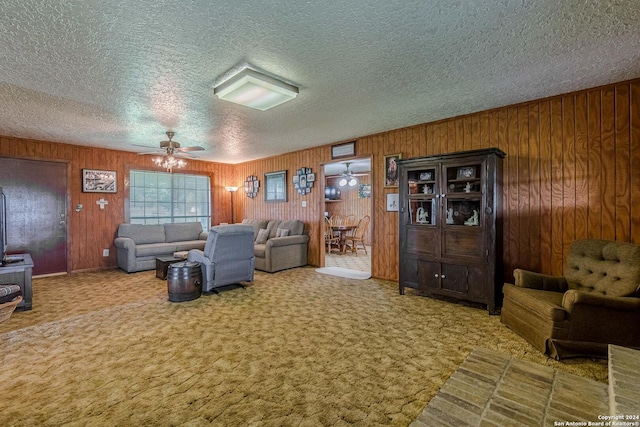 carpeted living room with wood walls, ceiling fan, and a textured ceiling