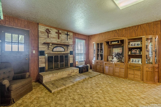 living room featuring carpet floors, a textured ceiling, a fireplace, and wood walls