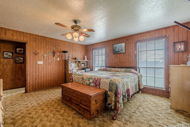 bedroom with wood walls, multiple windows, ceiling fan, and a textured ceiling