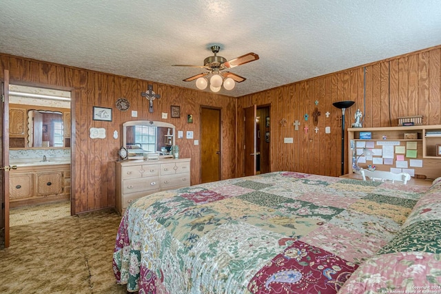 bedroom featuring ceiling fan, connected bathroom, wood walls, sink, and a textured ceiling