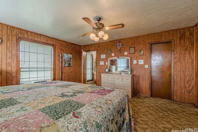 carpeted bedroom with a textured ceiling, wooden walls, and ceiling fan