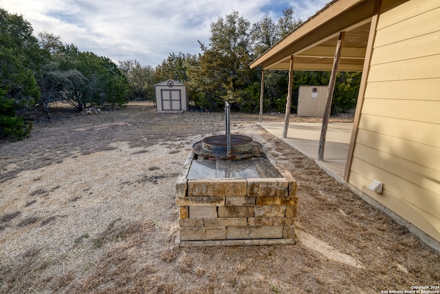 view of yard with a shed and an outdoor fire pit