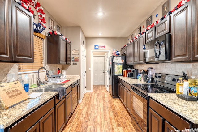 kitchen featuring light wood-type flooring, black appliances, tasteful backsplash, and sink