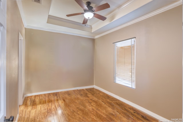 unfurnished room with light hardwood / wood-style floors, ceiling fan, a tray ceiling, and crown molding