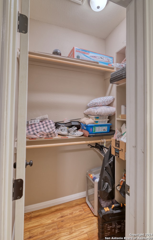 walk in closet with light hardwood / wood-style floors