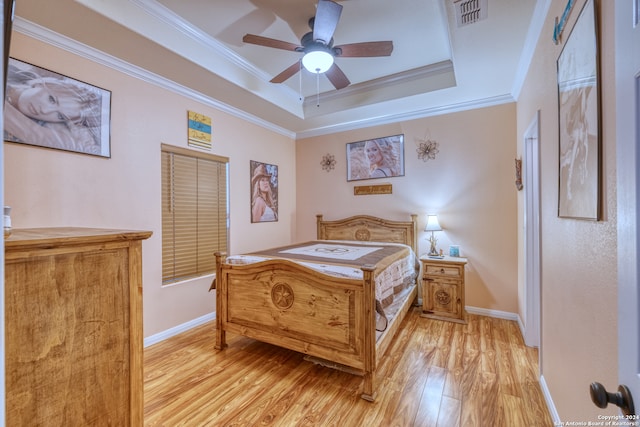 bedroom with ceiling fan, ornamental molding, a raised ceiling, and light hardwood / wood-style floors