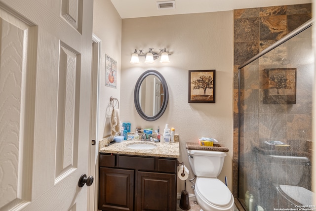 bathroom featuring a shower with door, vanity, and toilet