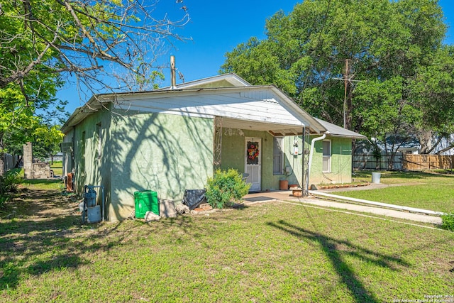 bungalow with stucco siding, a front lawn, and fence