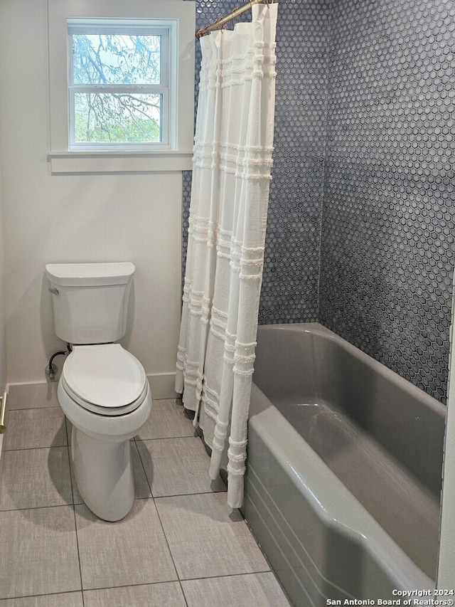 bathroom featuring shower / bath combination with curtain, tile patterned flooring, and toilet