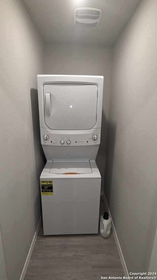 washroom featuring hardwood / wood-style floors and stacked washer and clothes dryer