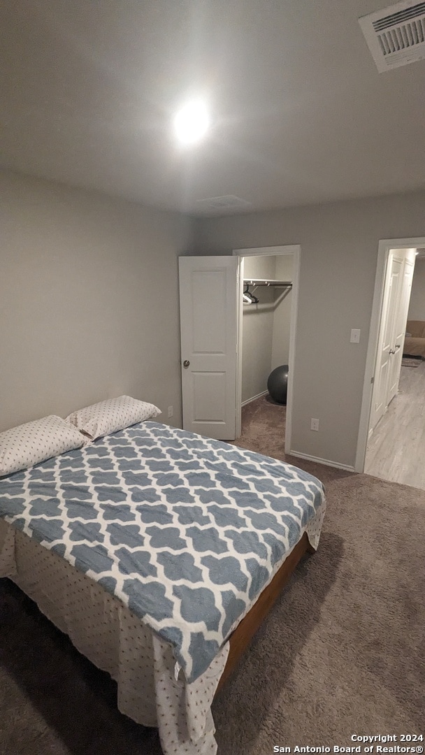 bedroom featuring light carpet, a closet, and a walk in closet