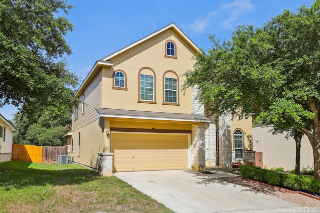 view of front of property with a front lawn, central air condition unit, and a garage