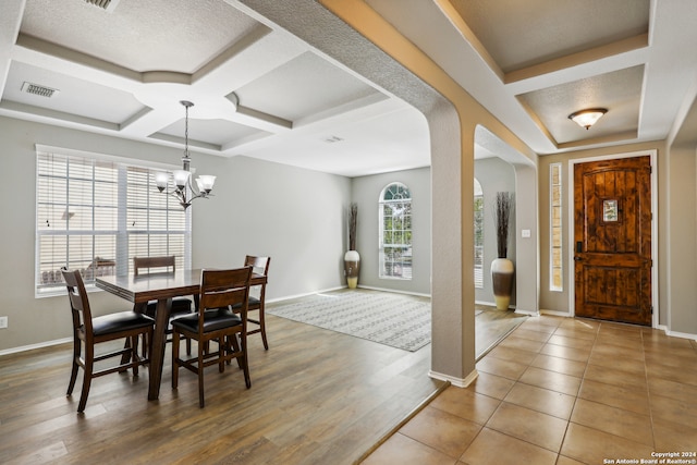 dining area with coffered ceiling, beamed ceiling, a textured ceiling, hardwood / wood-style floors, and a chandelier