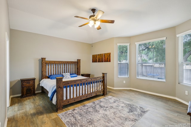 bedroom featuring ceiling fan, multiple windows, and dark wood-type flooring