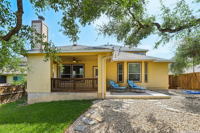 back of property featuring ceiling fan and a lawn