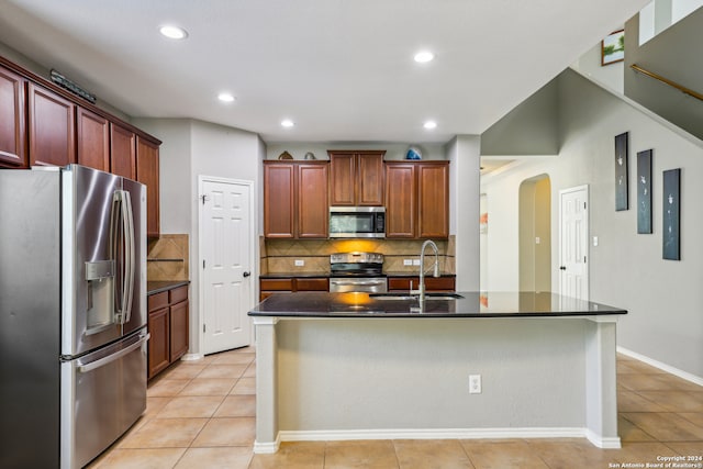 kitchen with stainless steel appliances, a center island with sink, light tile patterned floors, and sink