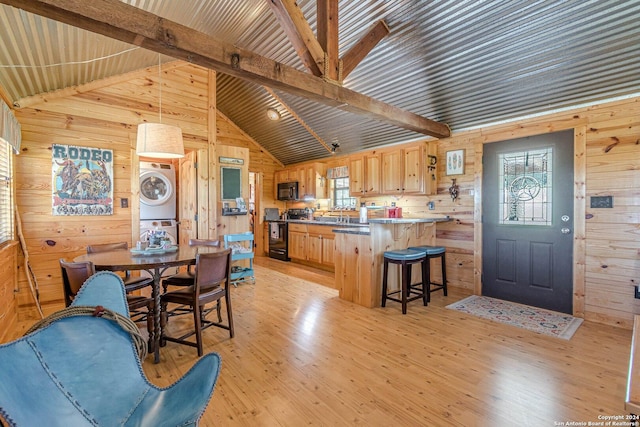 117 Hawk Rd, Fredericksburg, TX 78624 - kitchen with wood walls, stacked washing maching and dryer, black appliances, and a healthy amount of sunlight
