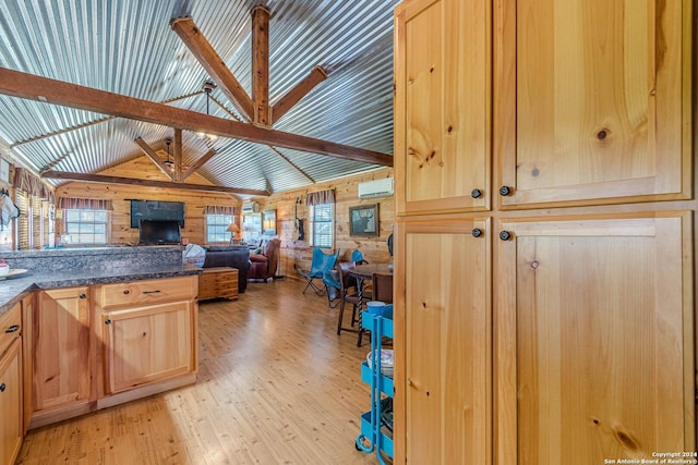 117 Hawk Rd, Fredericksburg, TX 78624 - kitchen featuring open floor plan, dark countertops, light wood-style floors, wood walls, and light brown cabinets