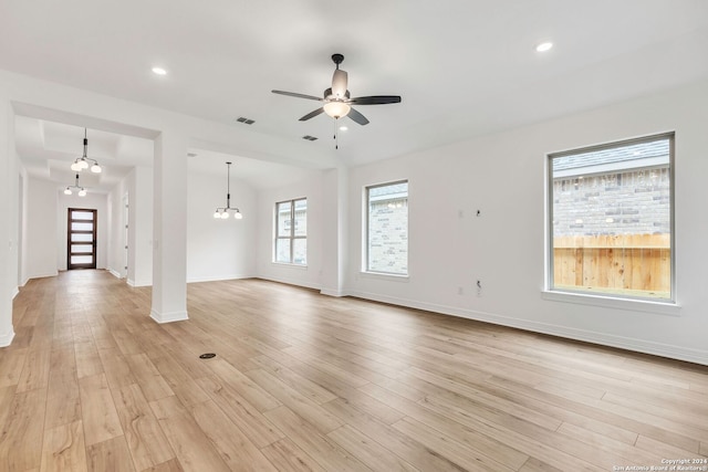 unfurnished living room with light wood-type flooring and ceiling fan with notable chandelier