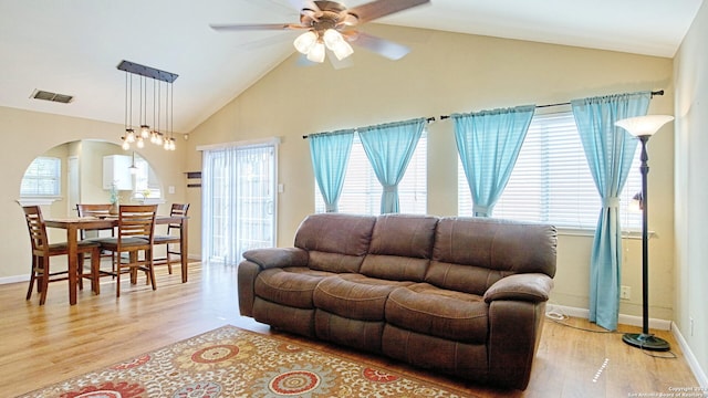 living room featuring light wood-type flooring, vaulted ceiling, a wealth of natural light, and ceiling fan