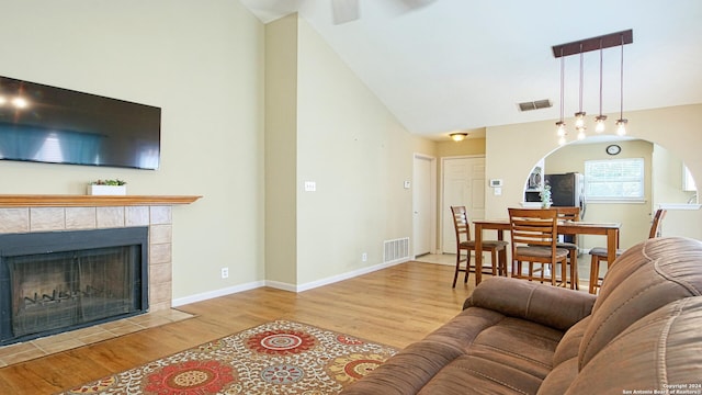 living room featuring light hardwood / wood-style floors, a fireplace, and high vaulted ceiling