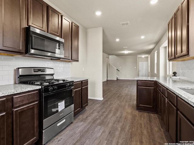 kitchen featuring light stone counters, hardwood / wood-style flooring, stainless steel appliances, backsplash, and dark brown cabinetry