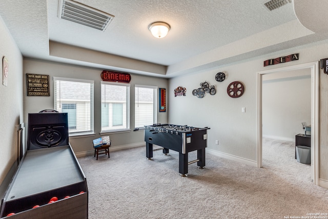 rec room featuring a textured ceiling, a tray ceiling, and light carpet