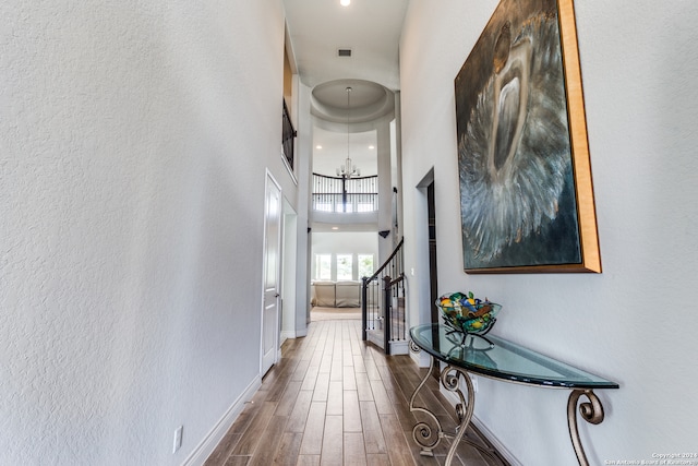 corridor with an inviting chandelier, a towering ceiling, and dark wood-type flooring