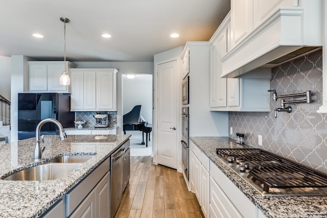 kitchen featuring light stone countertops, white cabinetry, appliances with stainless steel finishes, and custom range hood