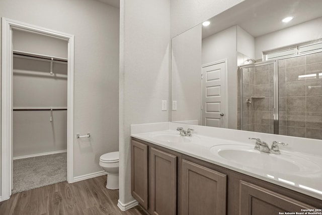 4951 Sandstone Way, San Antonio, TX 78222 - bathroom featuring a walk in closet, a shower stall, wood finished floors, and double vanity