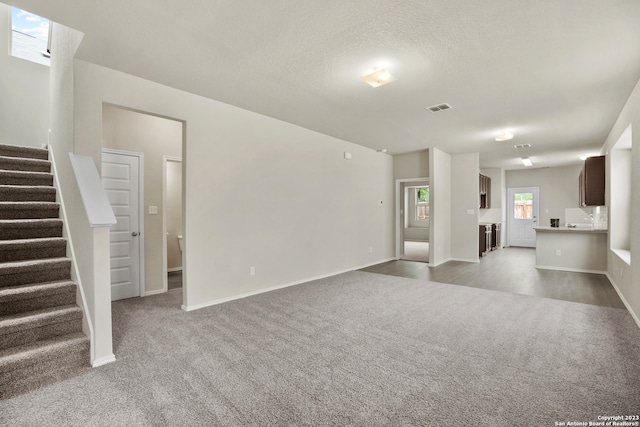 unfurnished living room featuring a textured ceiling and carpet floors