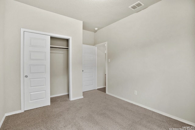 unfurnished bedroom featuring a textured ceiling, carpet, and a closet