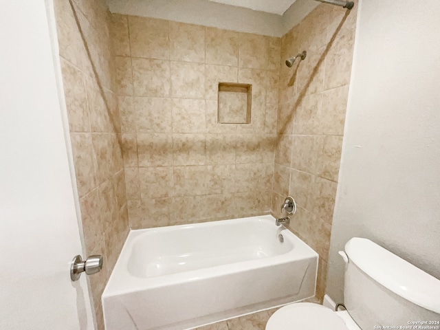 bathroom featuring tiled shower / bath combo and toilet