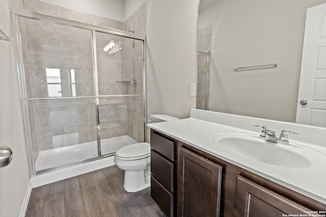 bathroom with walk in shower, vanity, hardwood / wood-style floors, and toilet