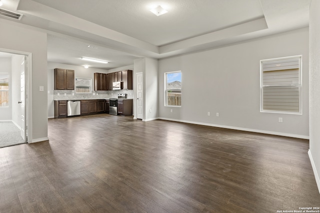 unfurnished living room with a raised ceiling and dark hardwood / wood-style flooring