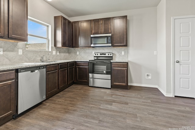 kitchen featuring appliances with stainless steel finishes, light wood-type flooring, and dark brown cabinets